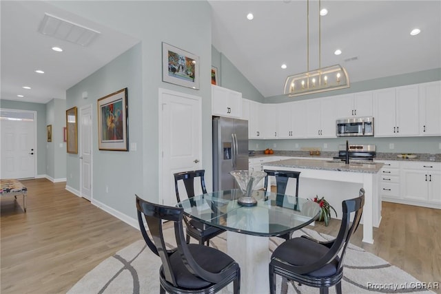 926 Old Saint Johns Rd, Irvington, VA 22480 - dining room featuring light wood finished floors, lofted ceiling, baseboards, and recessed lighting