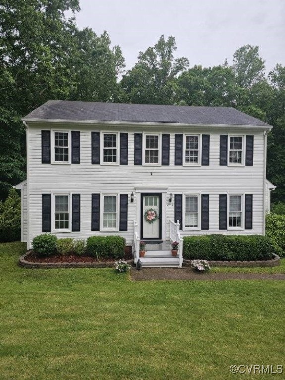 colonial-style house featuring a front lawn