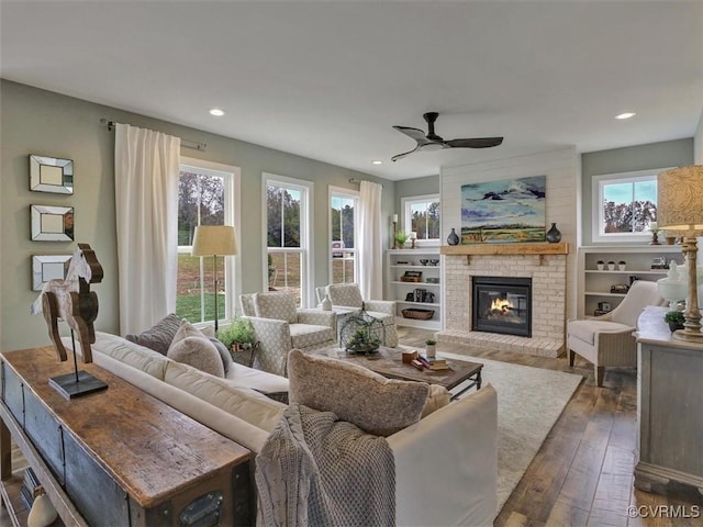 living room with wood-type flooring, a fireplace, a ceiling fan, and recessed lighting