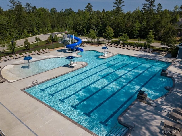 view of swimming pool featuring a water slide, fence, and a patio