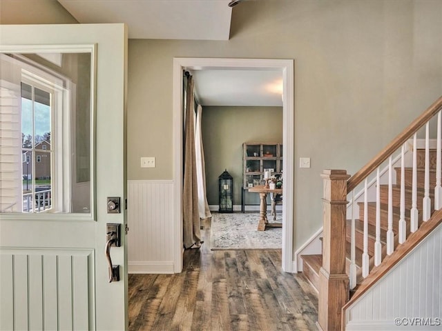 entrance foyer with wood finished floors, a wainscoted wall, and stairway