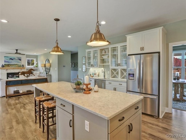 kitchen with stainless steel appliances, healthy amount of natural light, a center island, light wood finished floors, and recessed lighting