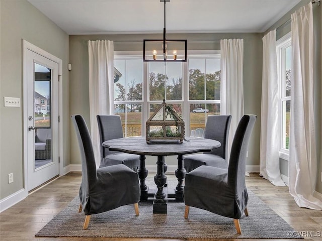 dining space featuring a chandelier, wood finished floors, and baseboards