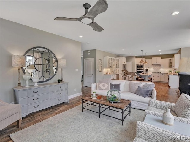 living room with a ceiling fan, wood finished floors, recessed lighting, and baseboards