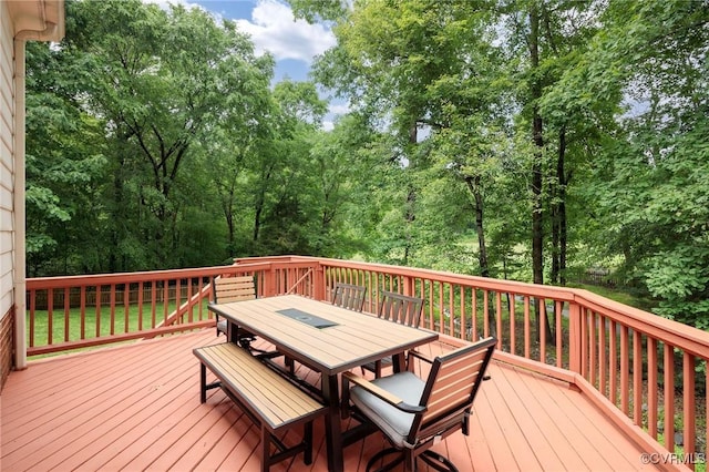 deck featuring outdoor dining area and view of scattered trees