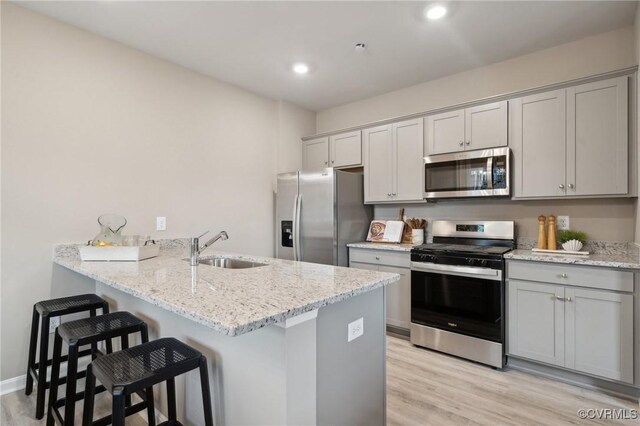 5916 Banyan Ln, Chesterfield, VA 23234 - kitchen featuring appliances with stainless steel finishes, a sink, gray cabinets, a kitchen breakfast bar, and light wood-style flooring