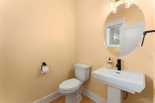 bathroom with baseboards, toilet, and a sink