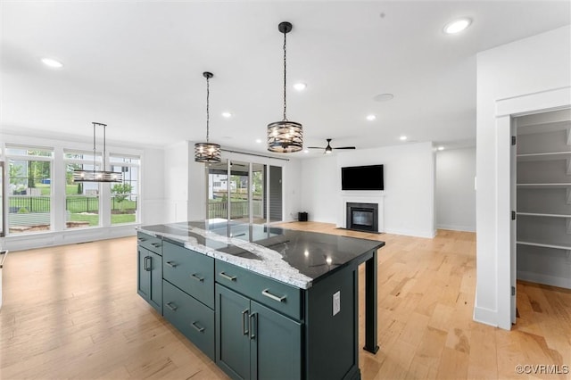 kitchen with a glass covered fireplace, a chandelier, light wood-style flooring, healthy amount of natural light, and recessed lighting