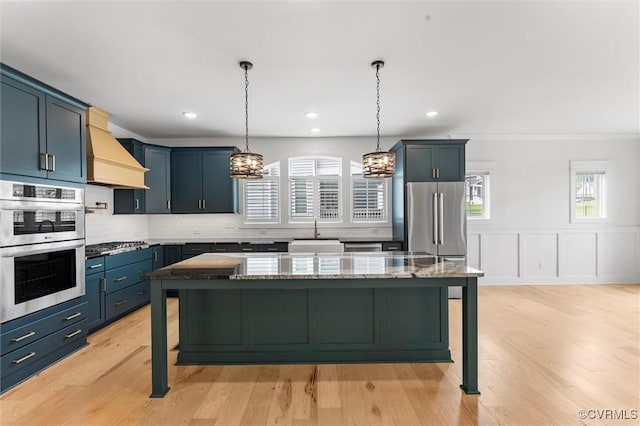 kitchen with custom range hood, a sink, a kitchen bar, stainless steel appliances, and tasteful backsplash