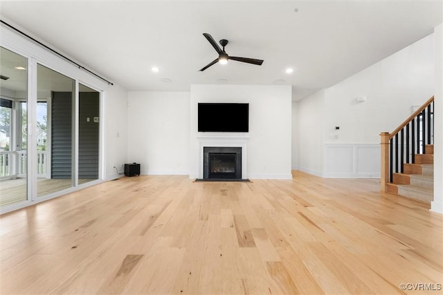 unfurnished living room with a ceiling fan, a fireplace with flush hearth, light wood finished floors, stairs, and recessed lighting