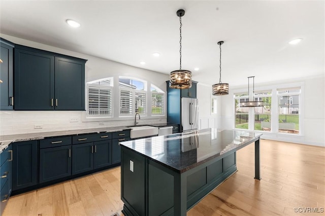 kitchen featuring appliances with stainless steel finishes, a chandelier, a sink, dark stone counters, and plenty of natural light