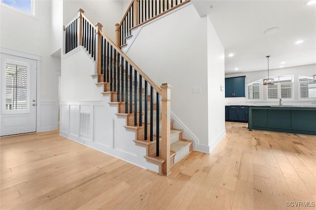 stairs featuring hardwood / wood-style flooring, a towering ceiling, recessed lighting, and a chandelier