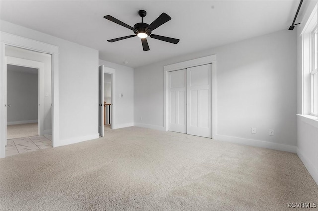 unfurnished bedroom featuring baseboards, a closet, carpet flooring, and ceiling fan