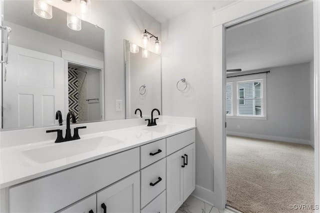 bathroom featuring baseboards, double vanity, and marble look tiles