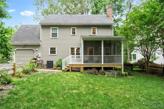 rear view of property featuring a chimney, central AC unit, an attached garage, a sunroom, and roof with shingles