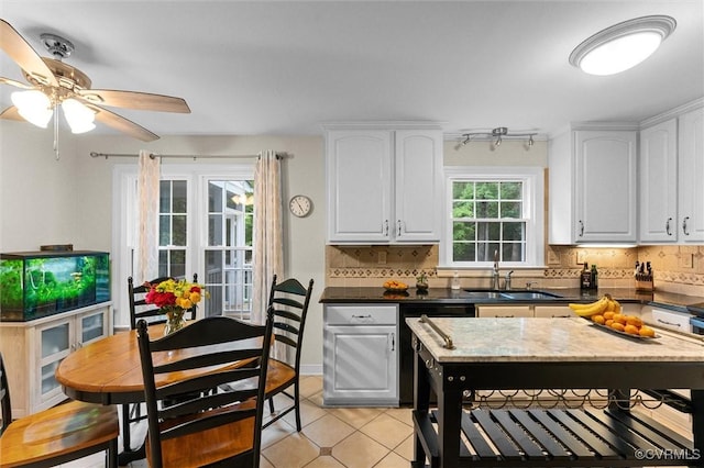 kitchen with a sink, decorative backsplash, white cabinetry, and light tile patterned flooring
