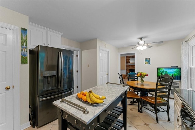 kitchen featuring stainless steel fridge with ice dispenser, white cabinetry, light tile patterned floors, a ceiling fan, and baseboards