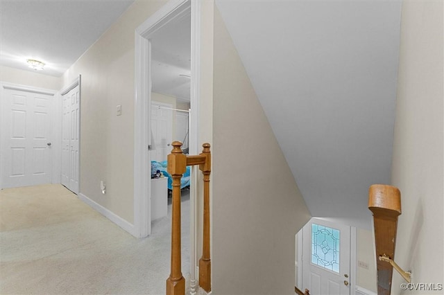 hallway featuring an upstairs landing, carpet, and baseboards