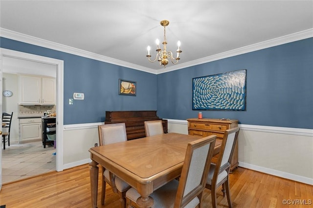 dining space with a chandelier, ornamental molding, light wood-type flooring, and baseboards