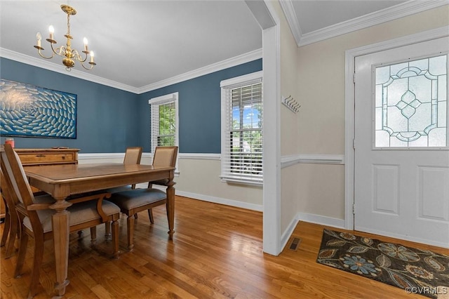 dining space with a chandelier, wood finished floors, ornamental molding, and baseboards