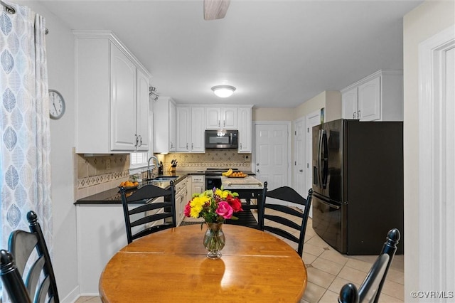 kitchen with appliances with stainless steel finishes, white cabinets, a sink, decorative backsplash, and light tile patterned flooring
