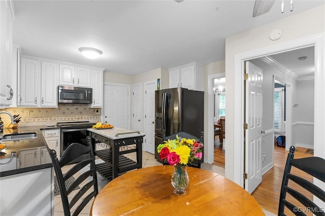 kitchen featuring appliances with stainless steel finishes, a sink, white cabinets, tasteful backsplash, and crown molding