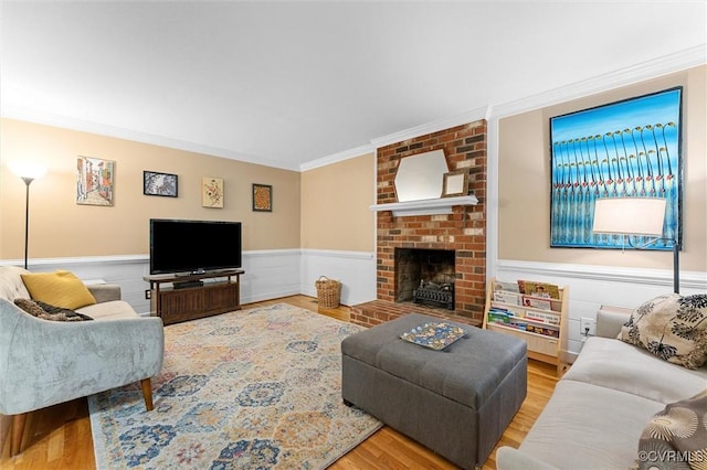 living area featuring wainscoting, ornamental molding, wood finished floors, and a fireplace