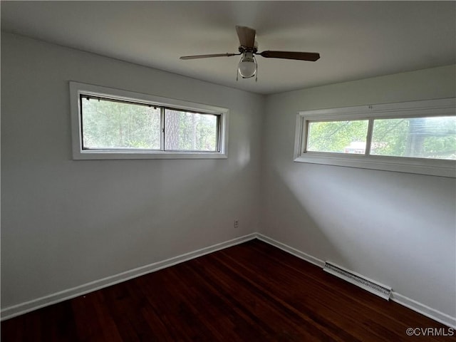 spare room featuring baseboards, dark wood-style floors, and a ceiling fan