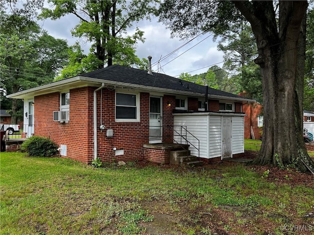 back of house with brick siding, a lawn, and cooling unit