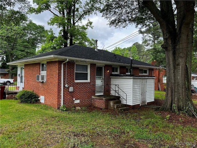 rear view of property with brick siding, a lawn, roof with shingles, and cooling unit