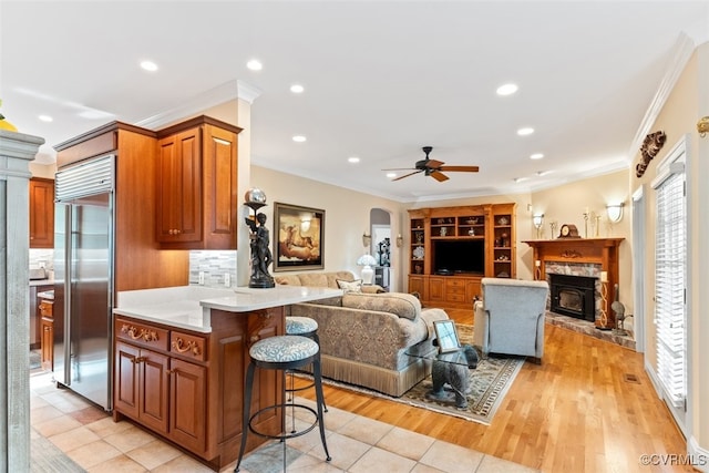 11216 Woodstock Heights Dr, Glen Allen, VA 23059 - kitchen with built in refrigerator, a kitchen bar, arched walkways, a stone fireplace, and open floor plan