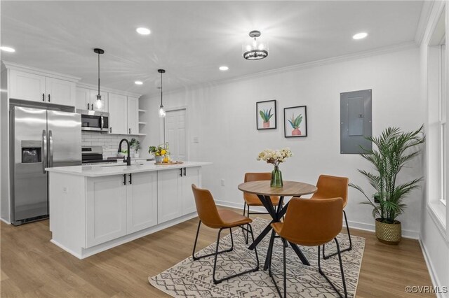 dining room featuring electric panel, baseboards, light wood finished floors, crown molding, and recessed lighting