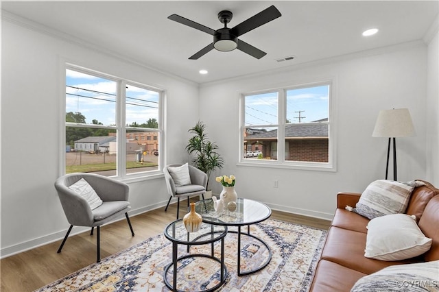 living room featuring ornamental molding, plenty of natural light, a ceiling fan, wood finished floors, and baseboards