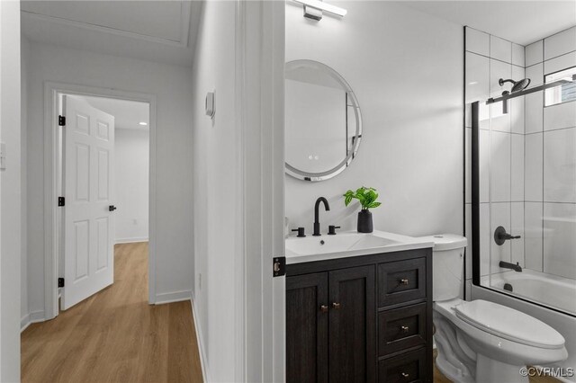 full bathroom featuring toilet, wood finished floors, vanity, and bath / shower combo with glass door