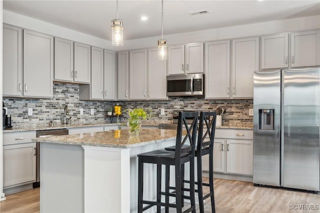7201 Hancock Chase Ct Unit J2, Chesterfield, VA 23832 - kitchen featuring appliances with stainless steel finishes, a sink, light wood-style floors, a kitchen island, and backsplash