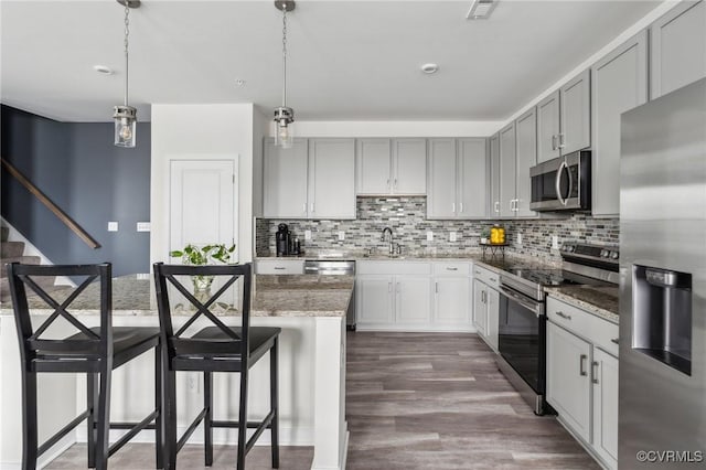 7201 Hancock Chase Ct Unit J2, Chesterfield, VA 23832 - kitchen with stainless steel appliances, a breakfast bar, light stone countertops, decorative backsplash, and decorative light fixtures