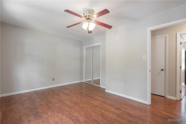 unfurnished bedroom featuring wood finished floors, a closet, baseboards, ceiling fan, and a textured ceiling