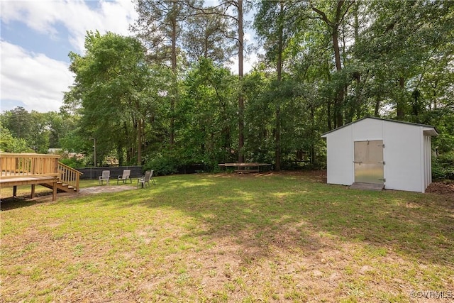 view of yard with a storage shed, an outbuilding, a wooden deck, and view of scattered trees