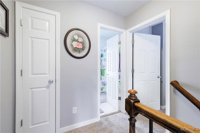 corridor featuring carpet, baseboards, and an upstairs landing