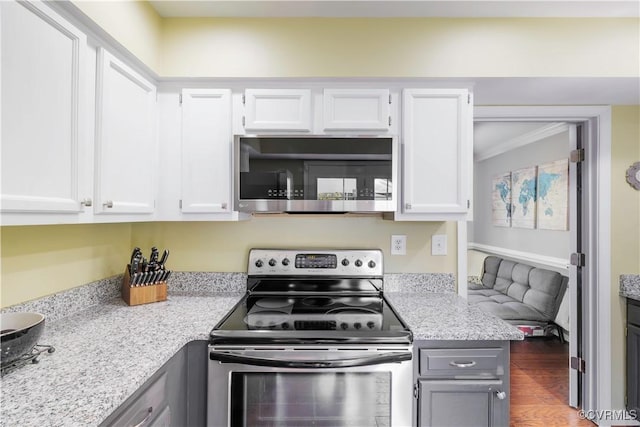 kitchen with stainless steel appliances, white cabinetry, light stone countertops, wood finished floors, and gray cabinetry