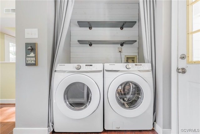 laundry area with washer and dryer, wood finished floors, baseboards, and healthy amount of natural light