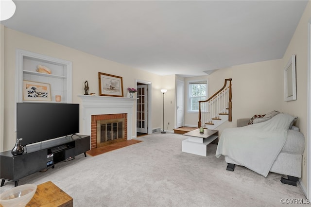 living room featuring carpet, stairway, a brick fireplace, and baseboards