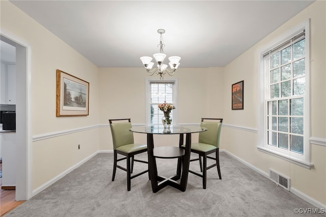 carpeted dining room featuring a chandelier, healthy amount of natural light, and baseboards