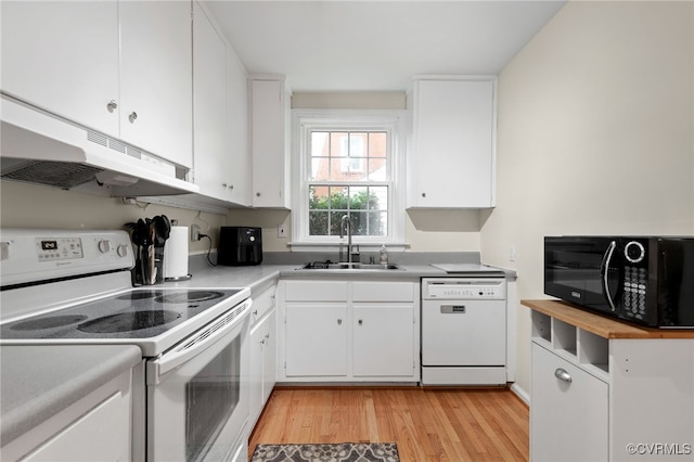 kitchen with white appliances, under cabinet range hood, a sink, light wood-style flooring, and white cabinetry