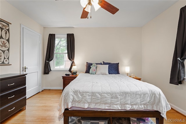 bedroom with light wood-style flooring, baseboards, and a ceiling fan