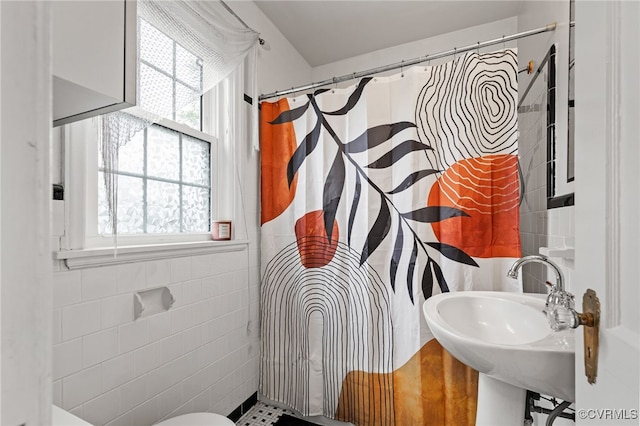 full bath featuring tile walls, healthy amount of natural light, a sink, and a shower with curtain