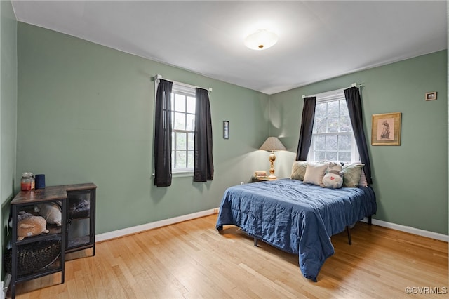 bedroom featuring wood finished floors, multiple windows, and baseboards