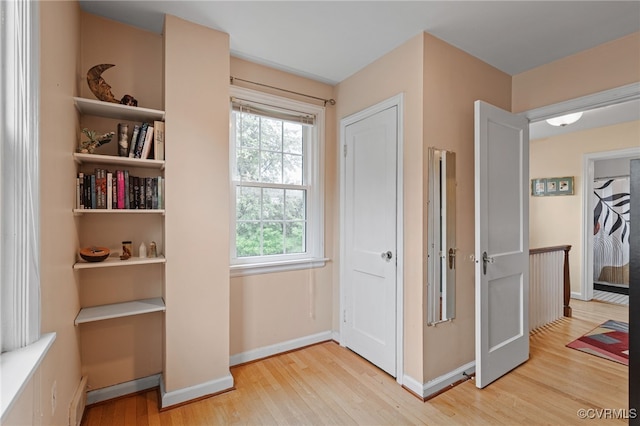 hall with light wood-style floors, baseboards, and a baseboard heating unit