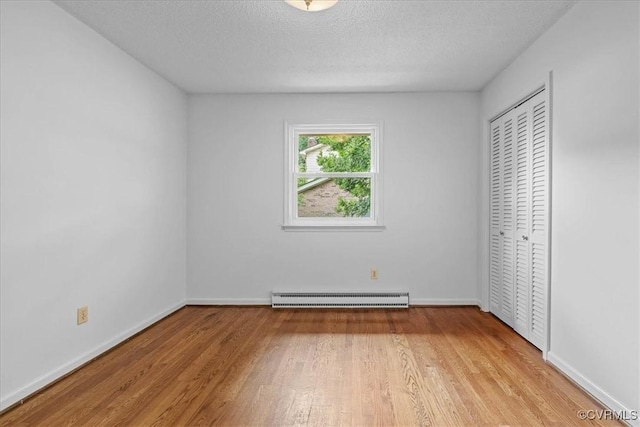 3304 N Marion Ave, Hopewell, VA 23860 - unfurnished bedroom with baseboard heating, light wood-style floors, baseboards, a closet, and a textured ceiling