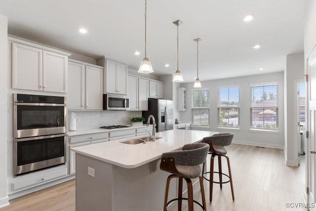 1906 Chartermark Dr, Midlothian, VA 23114 - kitchen featuring appliances with stainless steel finishes, a sink, a center island with sink, light wood finished floors, and a breakfast bar area